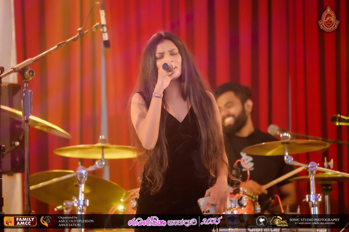 Kawya Erandi singing with eyes closed in front of a red curtain